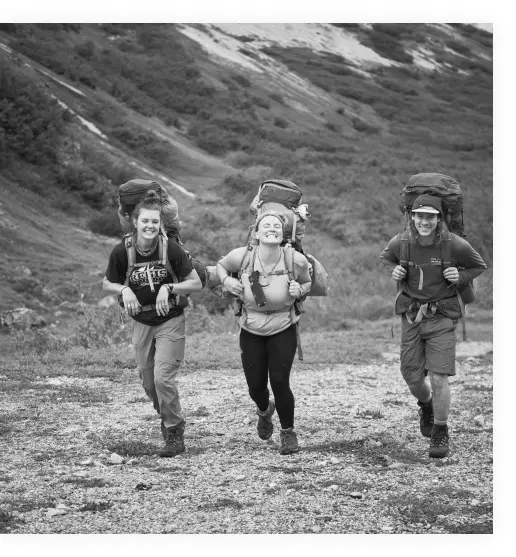 Three travelers with backpacks smiling and walking together