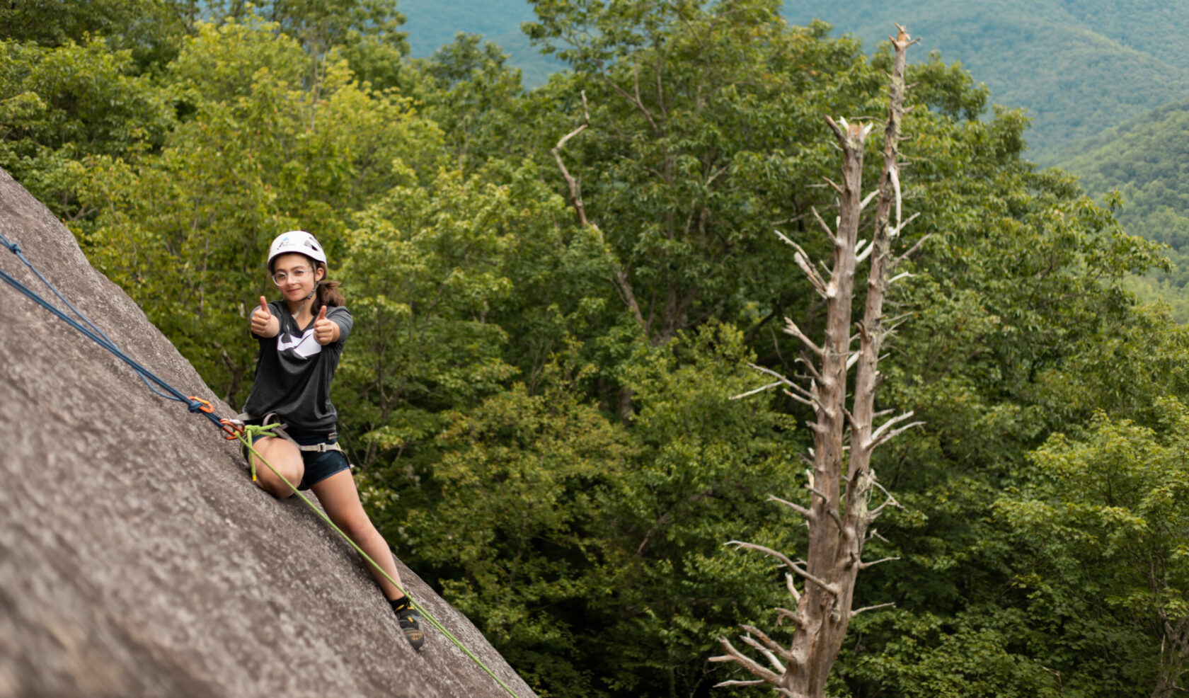 girl rock climbing giving 2 thumbs up