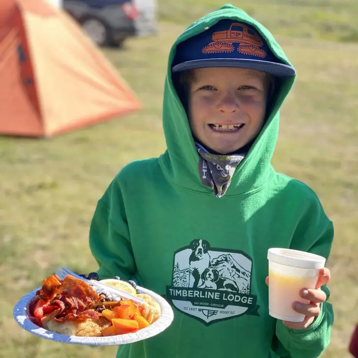 Young kid with plate of food on a campout trip