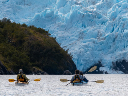 group sea kayaking towards a huge alaskan glacier