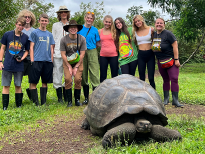Group in the Galapagos behind a giant tortoise