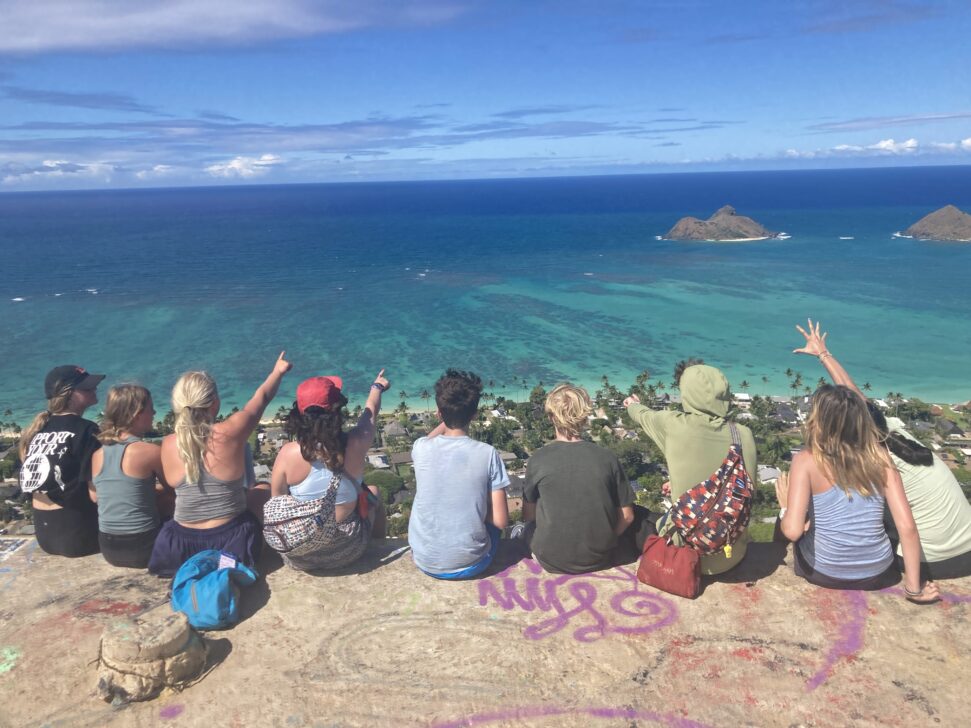 group sitting on a ledge looking over the ocean of Hawaii