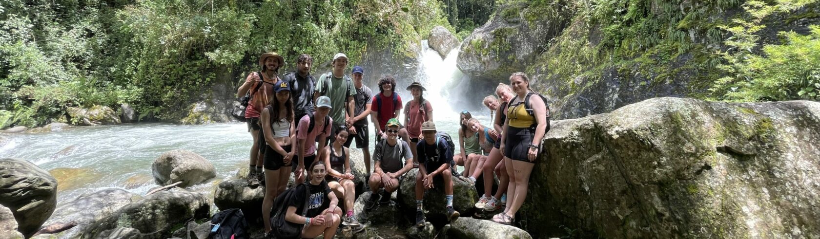 a group of student pose in front of a waterfall