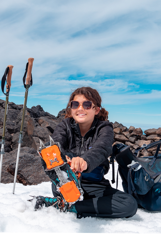 Girl putting on a crampon for mountaineering