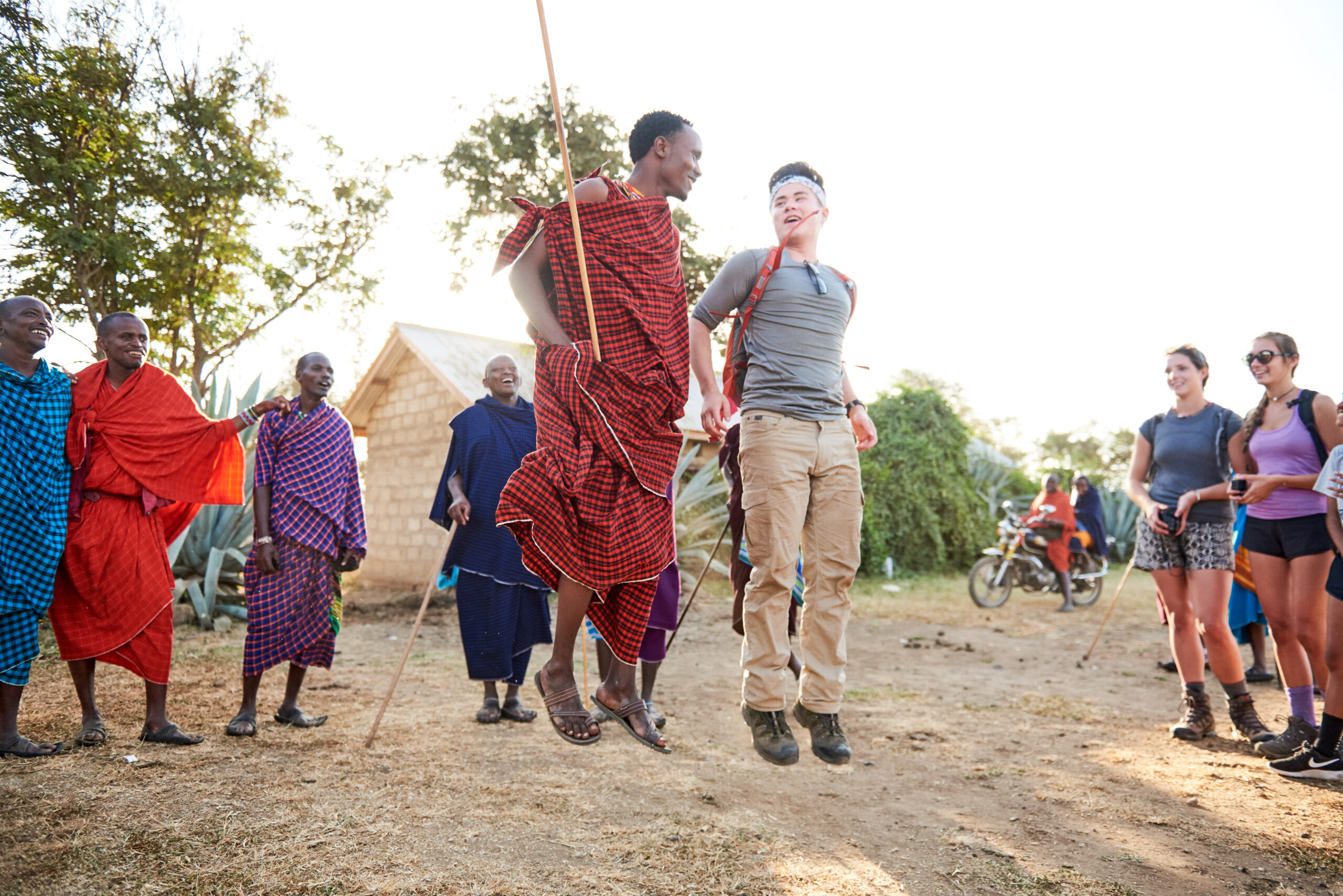 student jumps with Maasai man in a cultural visit