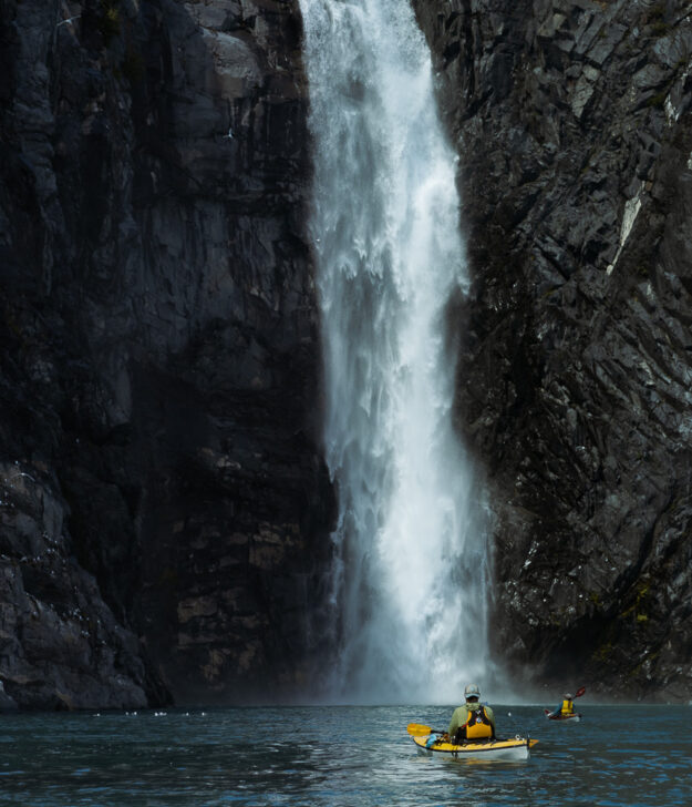 a kayaker sits and watches a waterfall