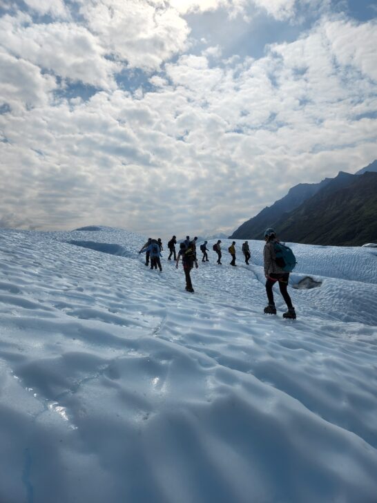 a group of students walk over a glacier