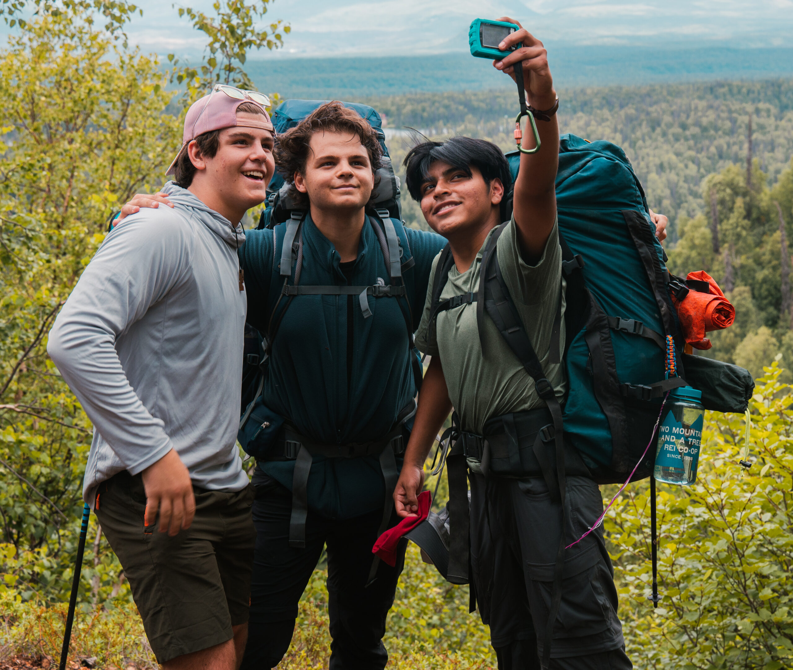 3 students taking a selfie while backpacking