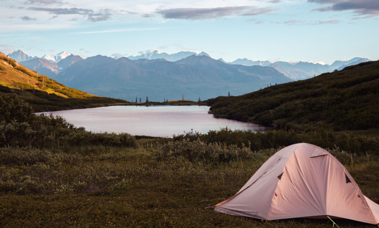 tent in front of a mountain and alpine lake in alaska
