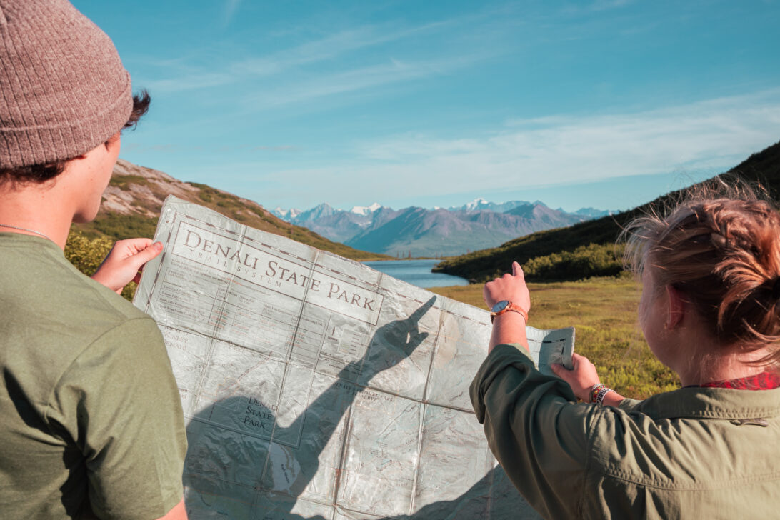 two people looking at a map of Denali State Park figuring out their route for backpacking