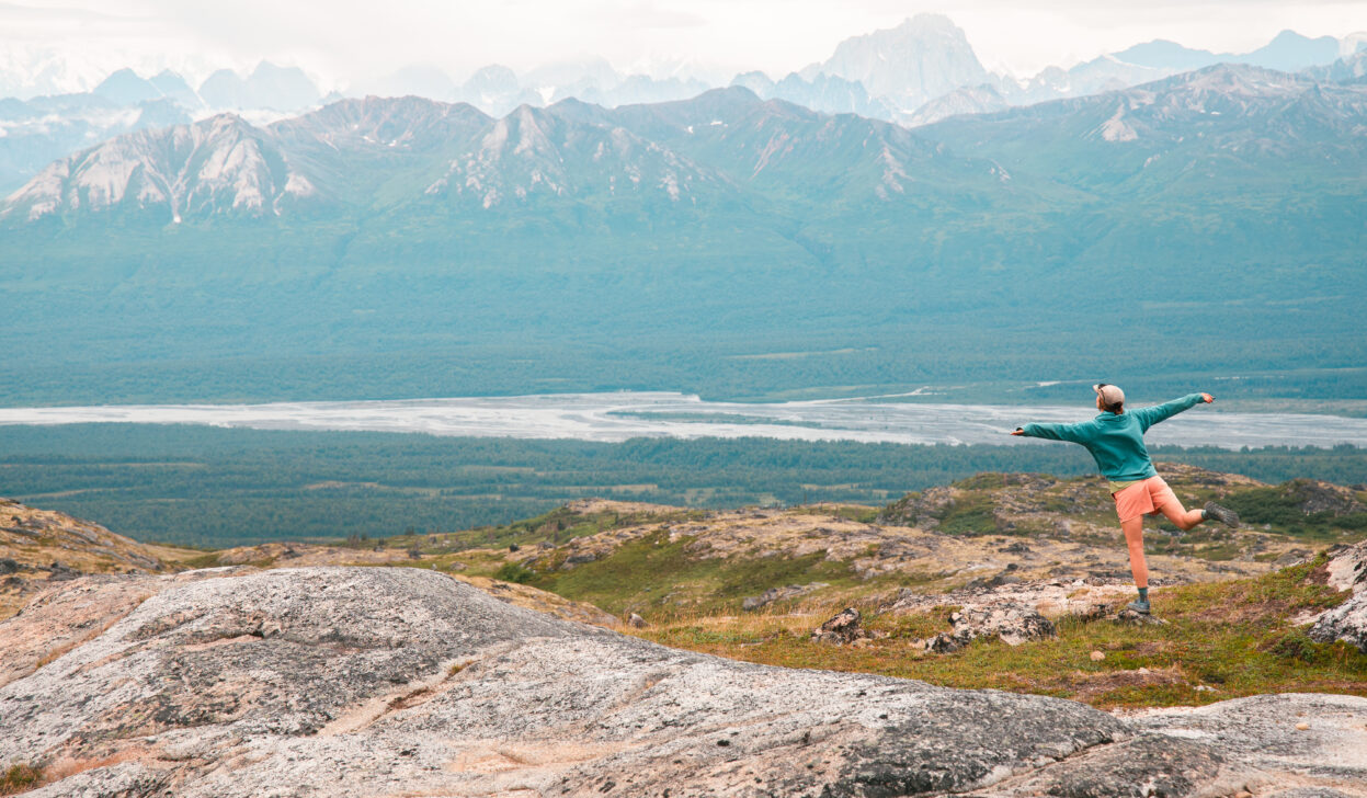 hiker posing in front of huge alaskan mountains