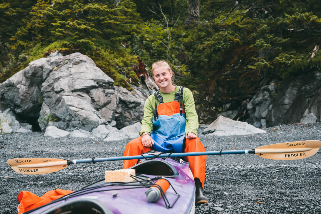 student sitting on a sea kayak on the shores of the prince William sounds