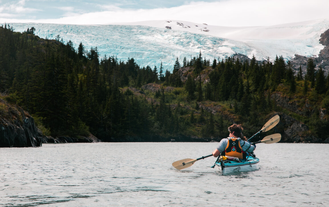 sea kayaker in front of alaskan wilderness and mountains in the ocean