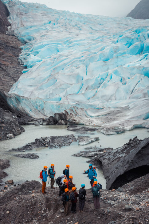 group learning to ice climb in front of a huge glacier