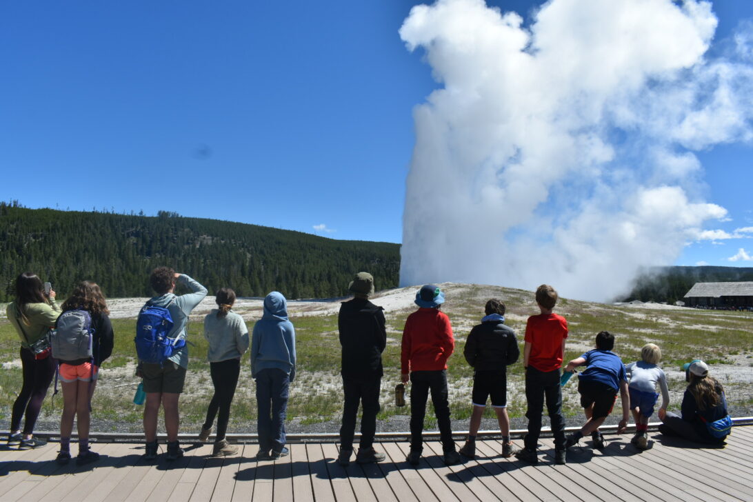 group watching old faithful geyser explode