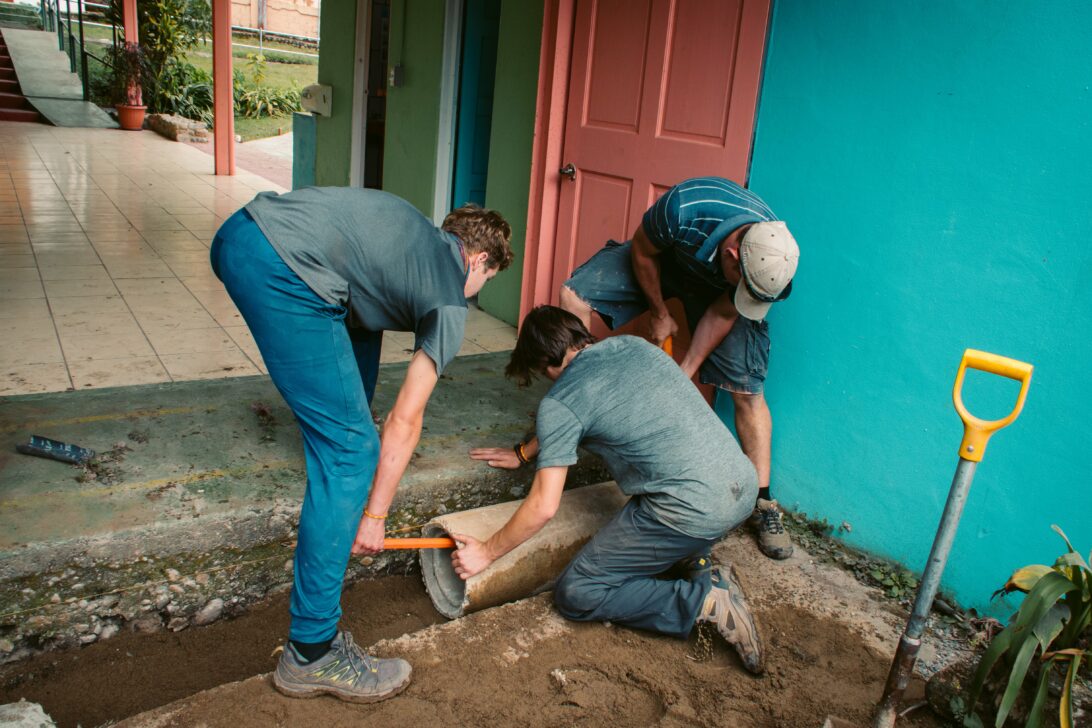 students placing a pipe down at a school in costa rica