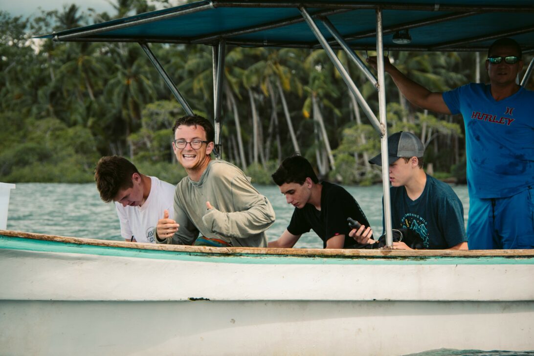 student giving a thumbs up in the front of a boat