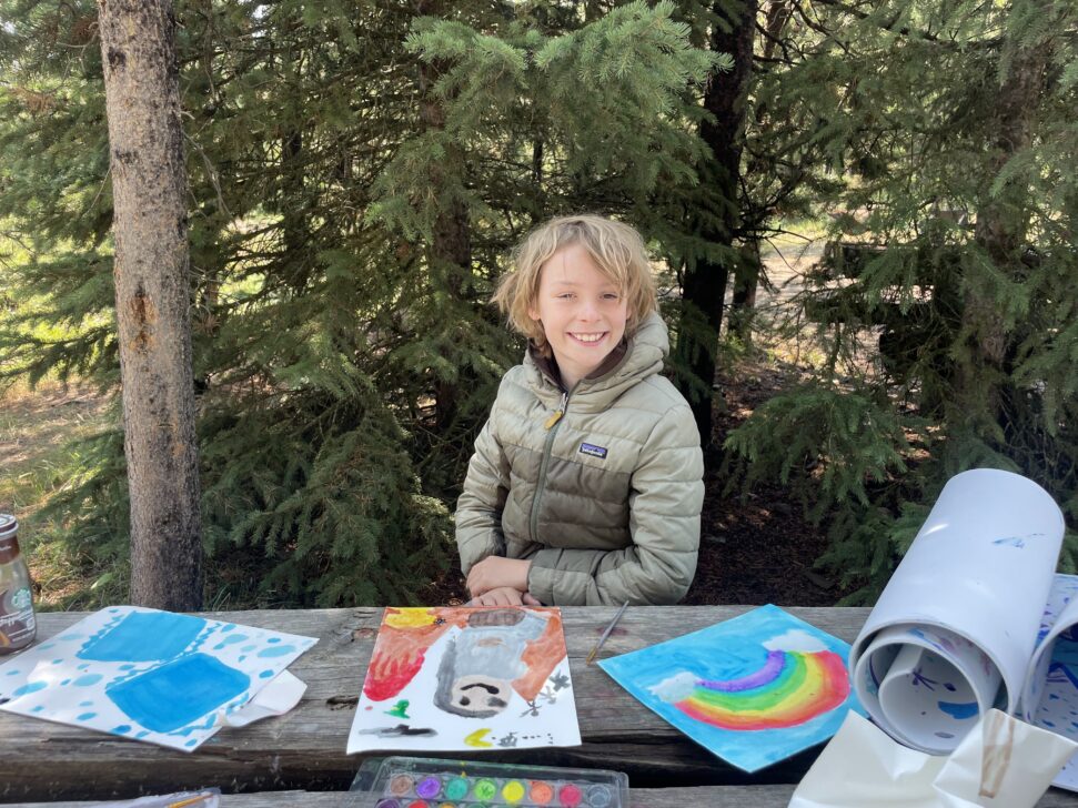 student with the art he just painted at a camping table