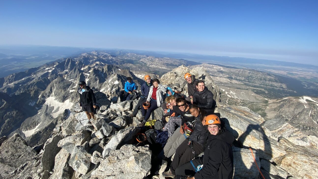 a group sits on the summit of the grand teton