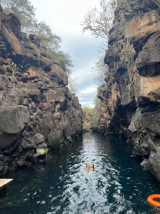 two students swimming in a river between 2 cliffs