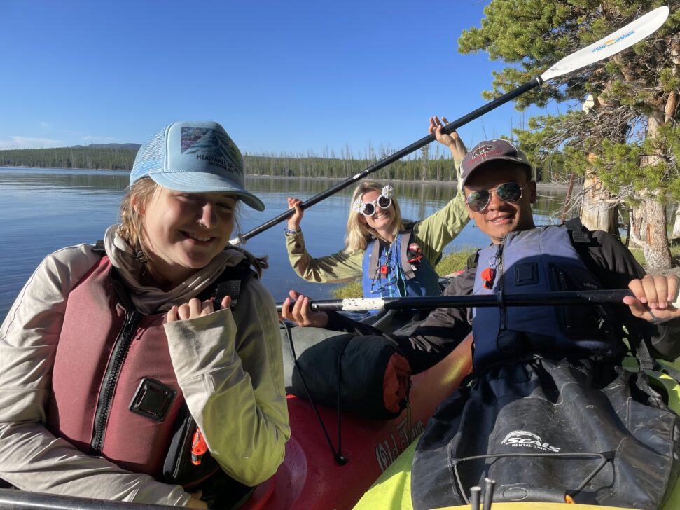 three students in sea kayaks on yellowstone lake