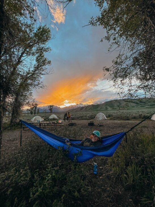 person in a hammock in front of tents in Grand Teton National Park