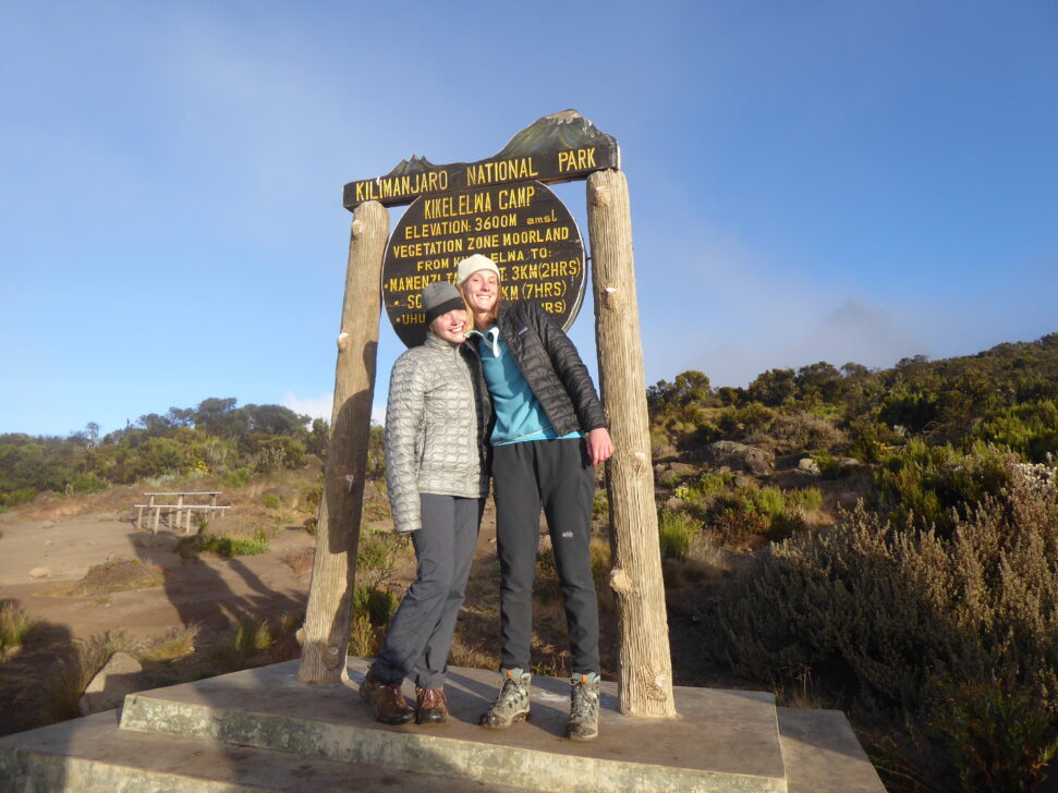 two students posing in front of a sign in Mt. Kilimanjaro national park