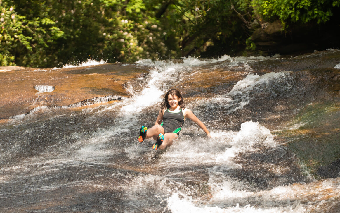 student sliding down natural water slide
