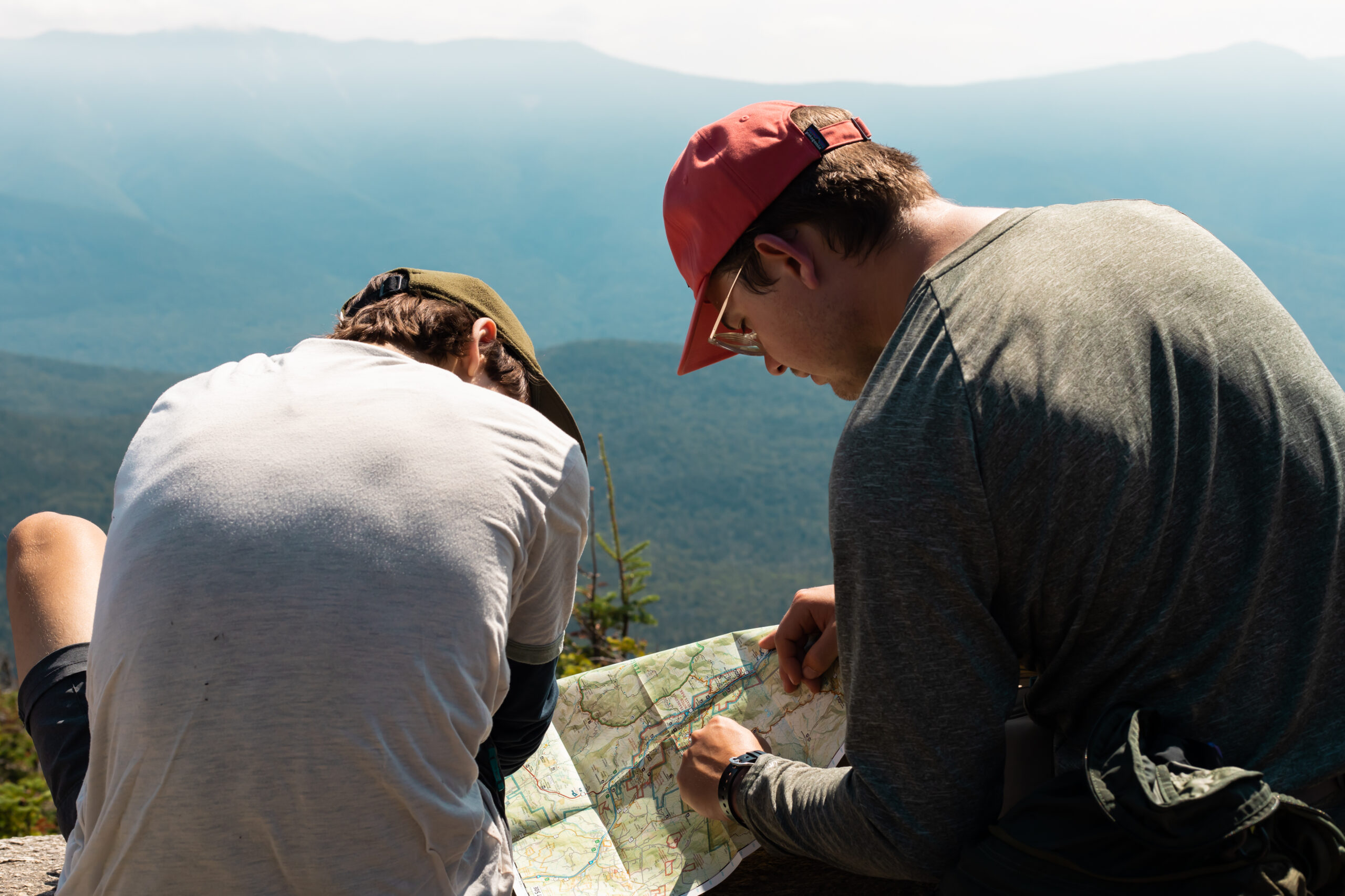 student and leader looking at a map on top of a mountain in the white mountains