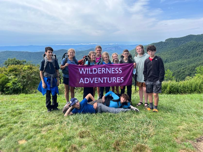 Group holding a wilderness adventures banner backpacking in the Pisgah National forest
