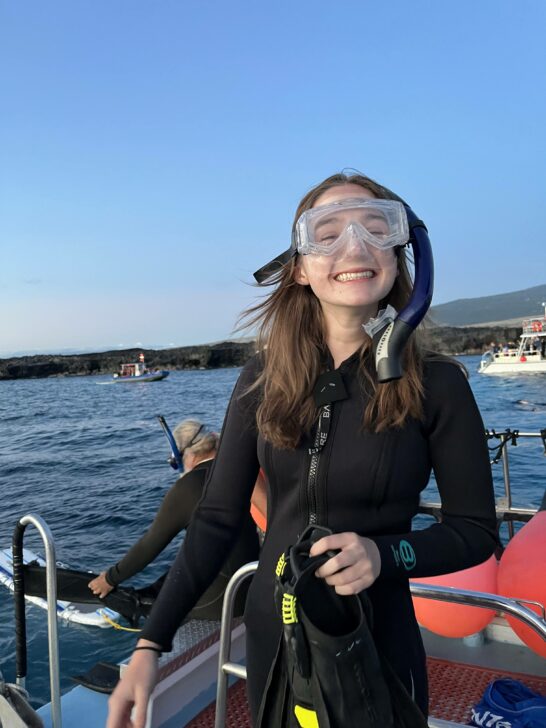 student on a boat with goggles getting ready to snorkel