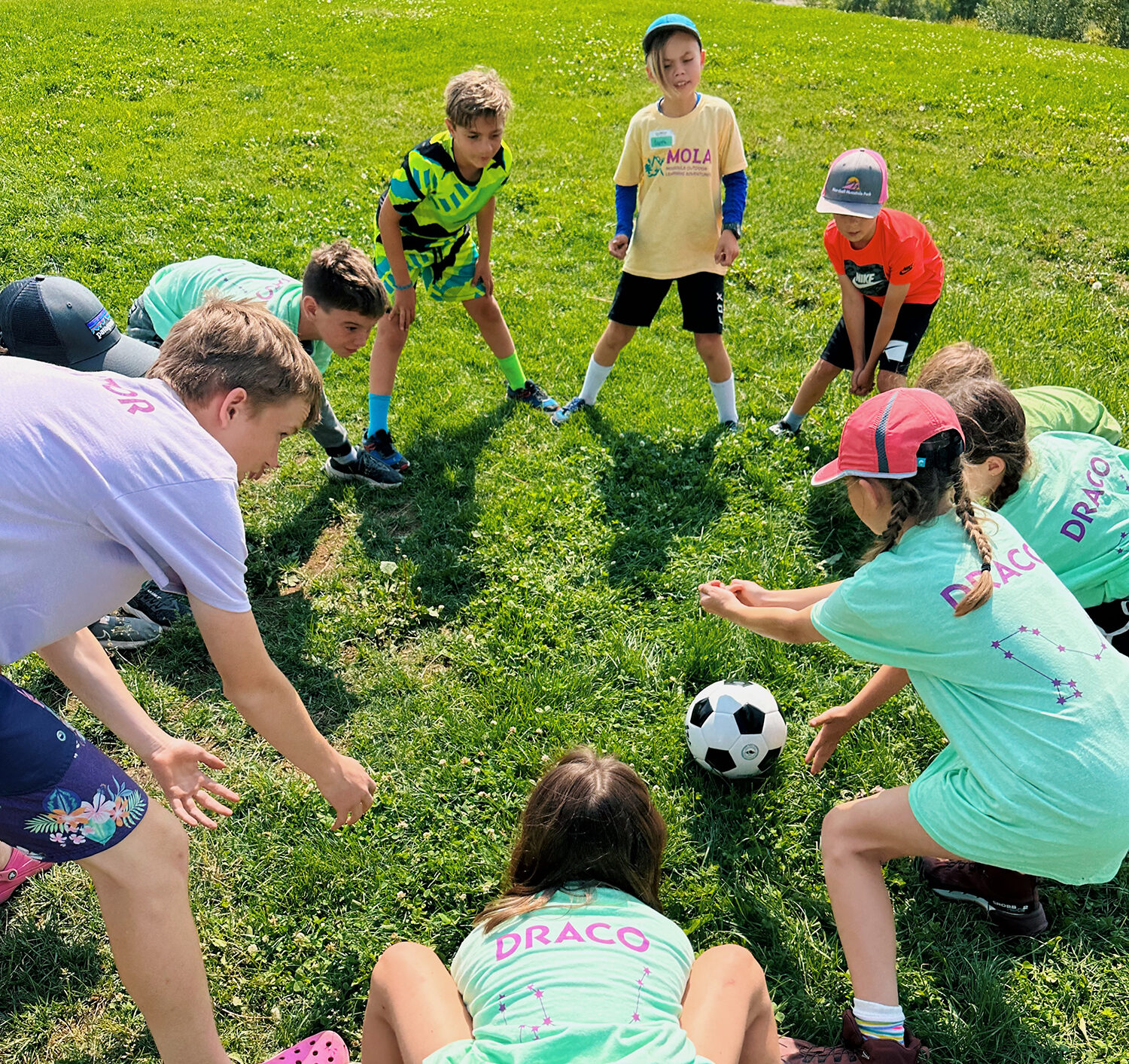 Group of campers in a circle passing around a soccer ball.