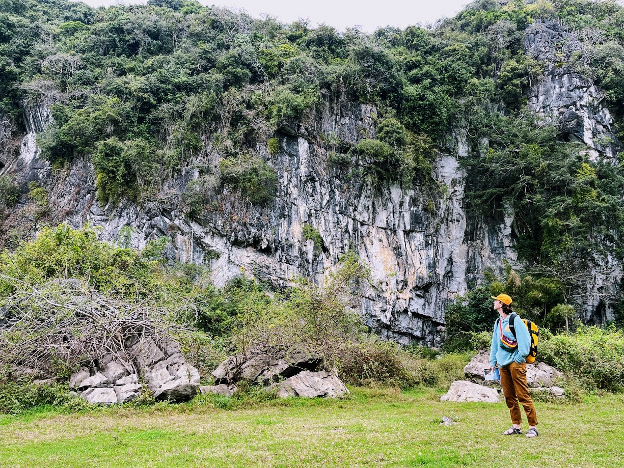 Man looking up at a rock wall in Vietnam
