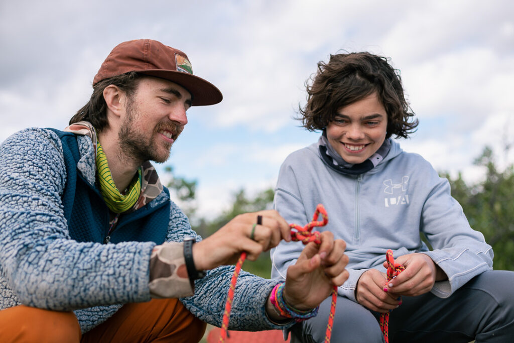Man teaching a student how to tie a climbing knot. 