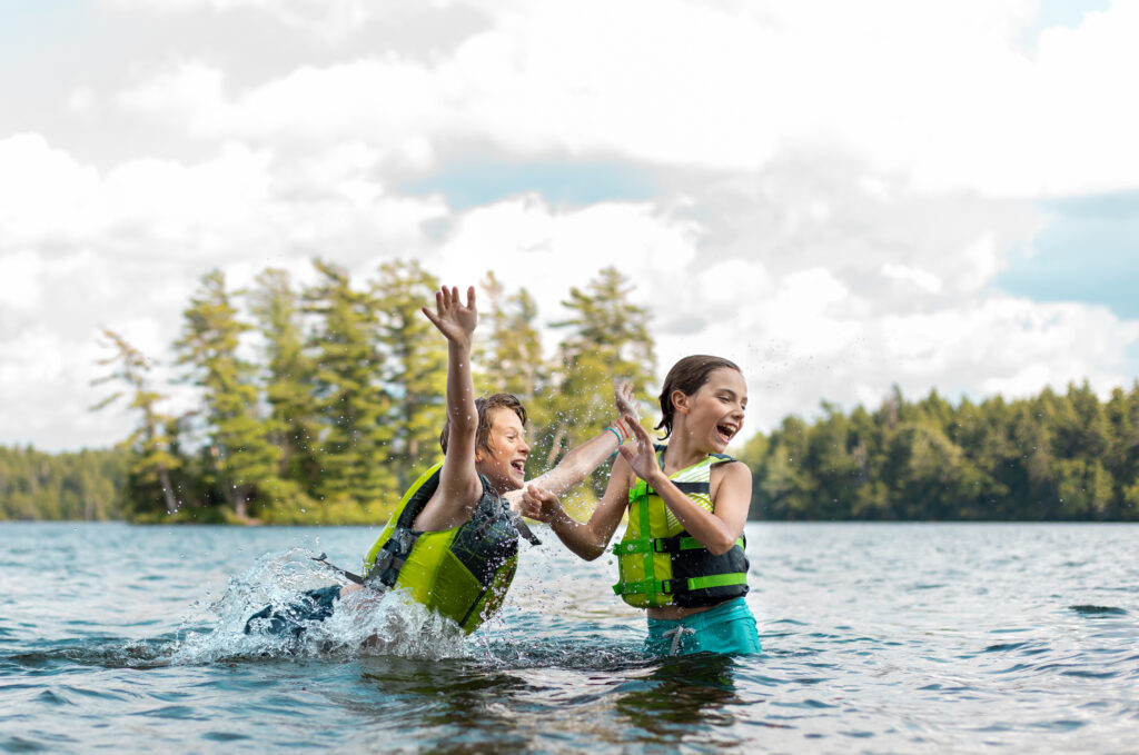 Two kids splashing in a lake.