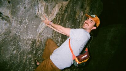 Man rock climbing in a cave smiling at the camera.