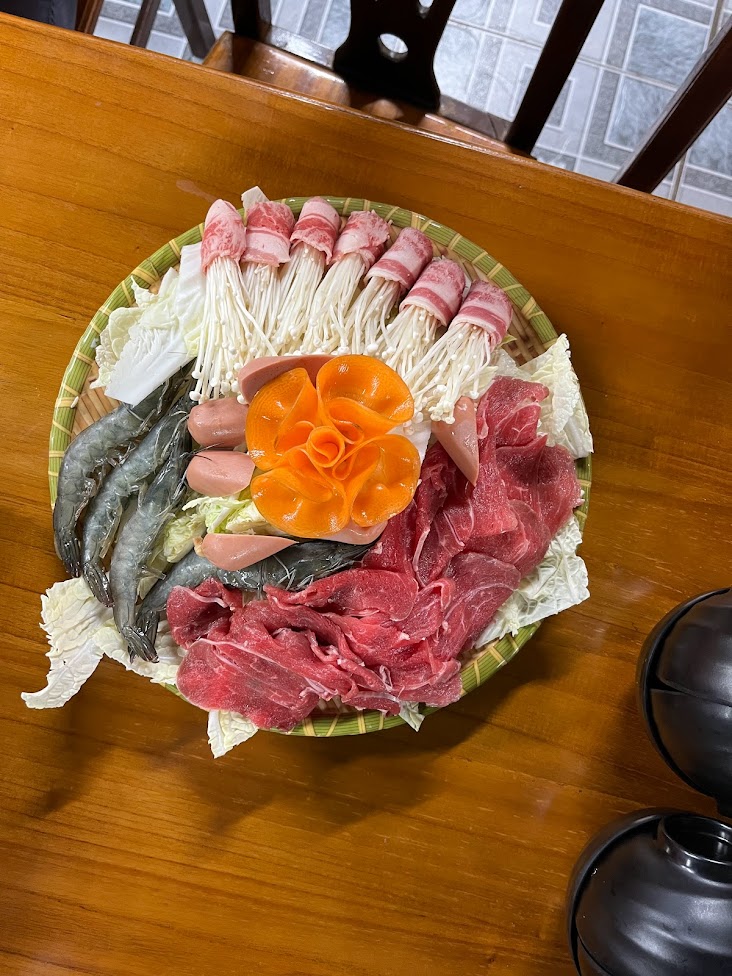 Plate of raw seafood, meat, and mushrooms arranged nicely. 