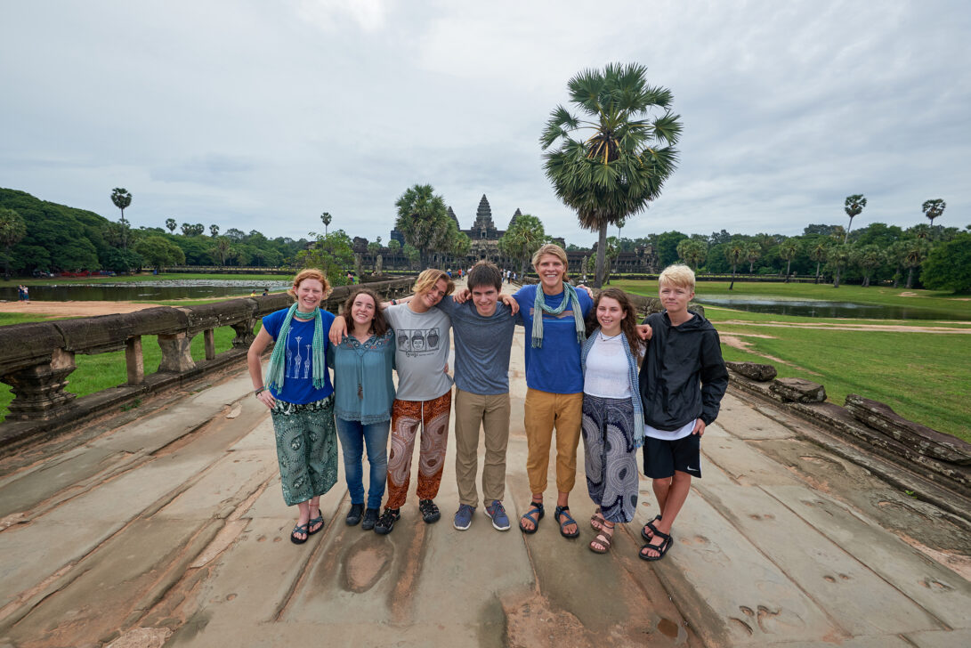 Group of students smiling with their arms around each other in front of ancient temple.