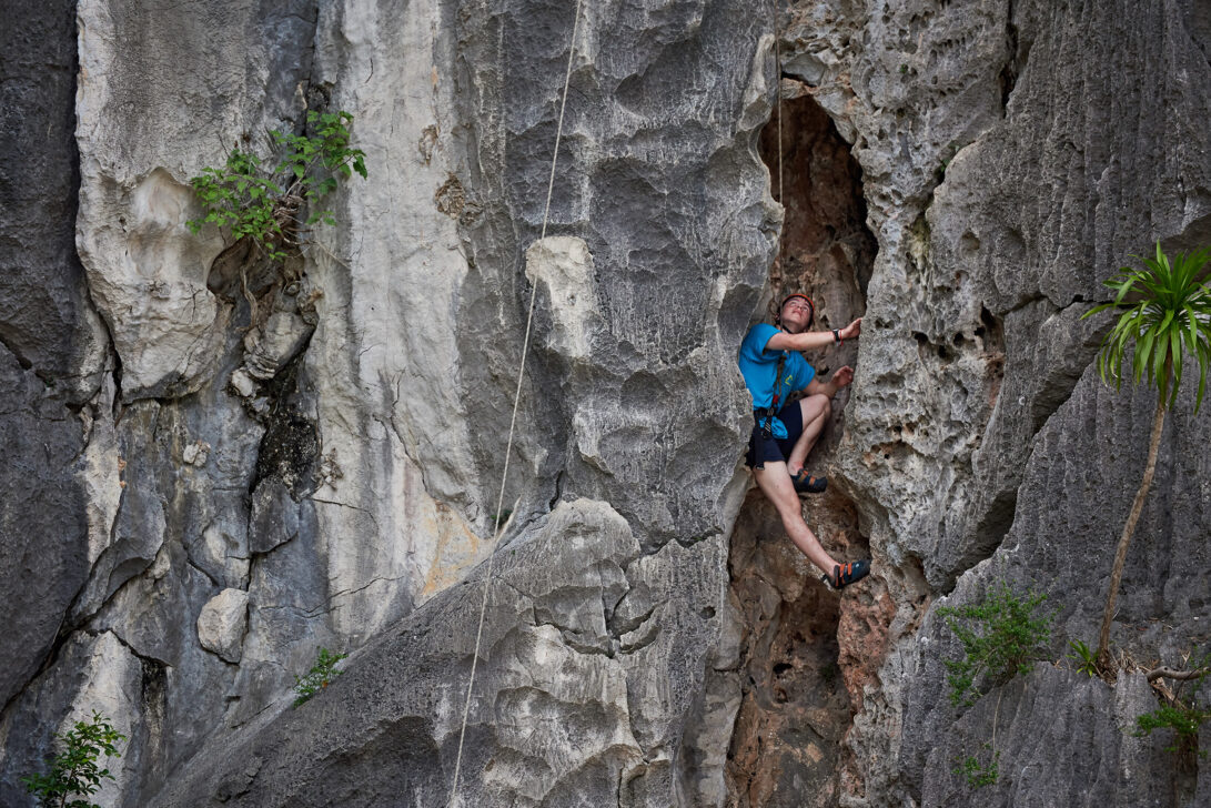 Young man rock climbing and looking up at route.