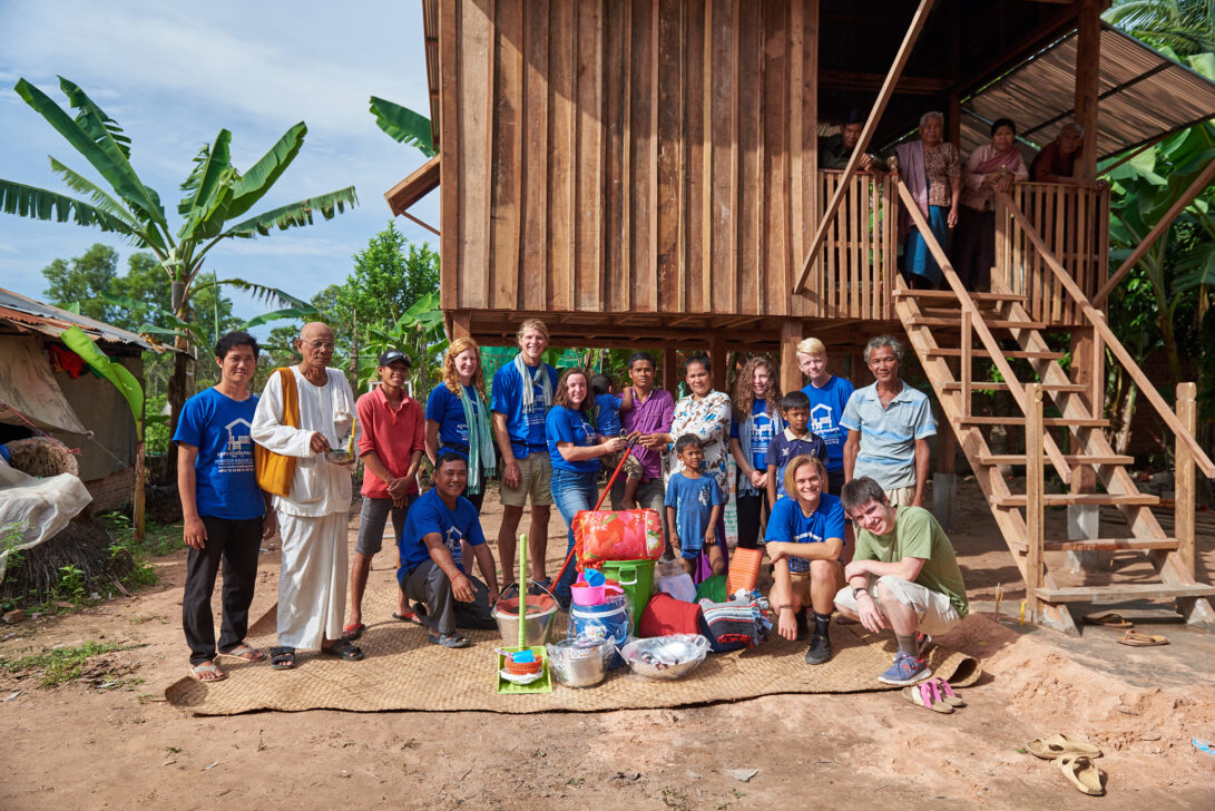 Group of travelers with local families at a newly built home in Vietnam.