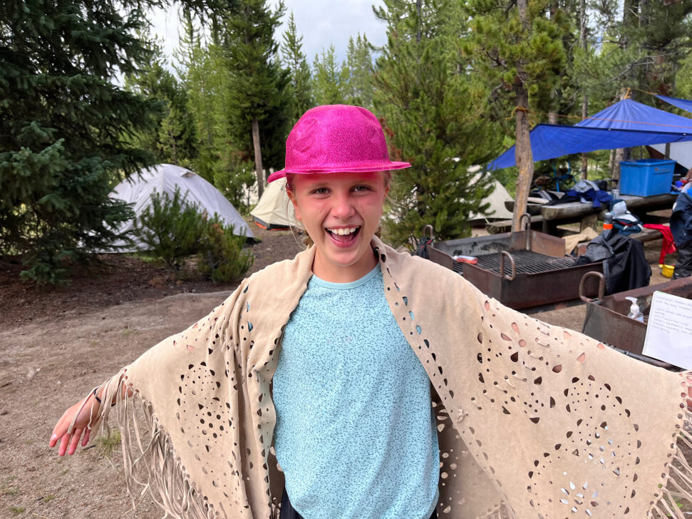 Young girl in a pink sparkly hat at a campground.