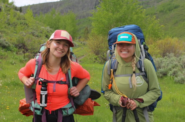 Two female Trip Leaders smiling with backpacking packs on.