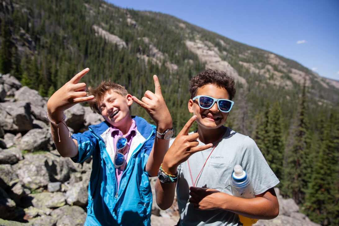 two young boys with rock on signs hiking in the mountains.