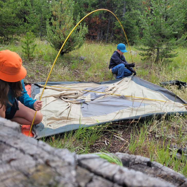 Two campers setting up a tent together.