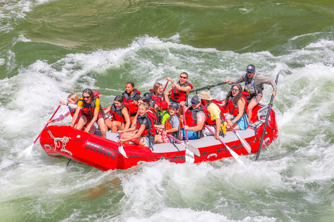 Group of travelers white water rafting through a rapid.