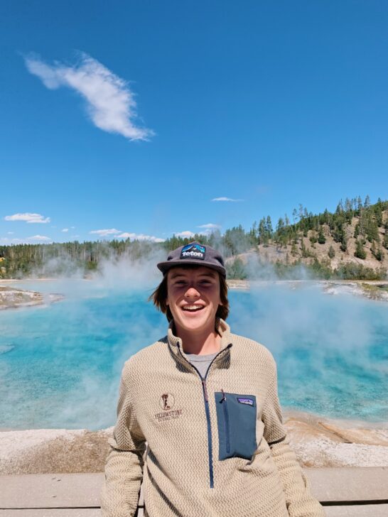 Student smiling in front of Yellowstone National Park features.