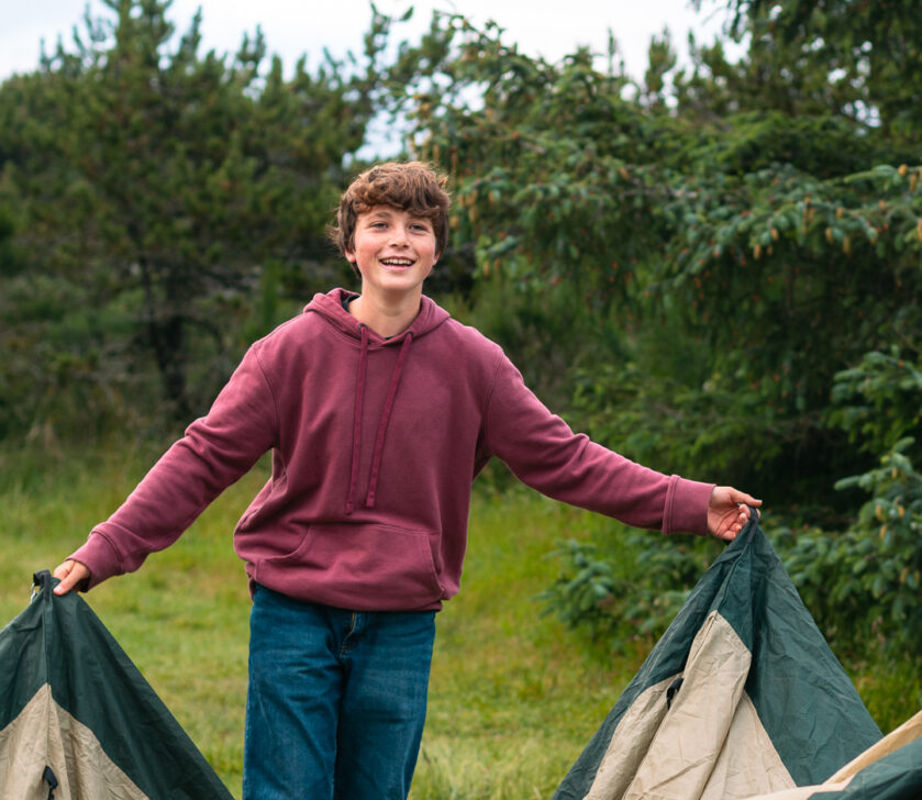 Student smiling while holding up a tent.