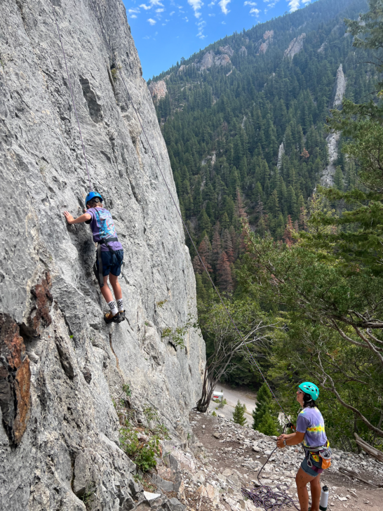 Young camper rock climbing on a granite wall.