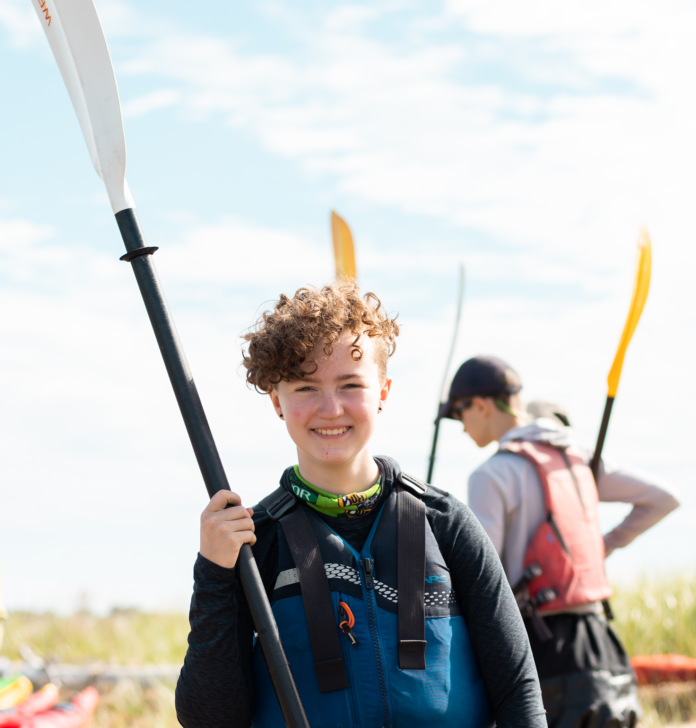 Person holding a paddle and smiling.