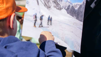Young boy admiring a photo of people mountaineering.
